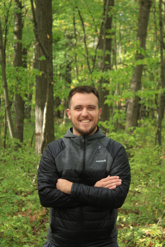 A picture of Eric Demers in front of a forest background